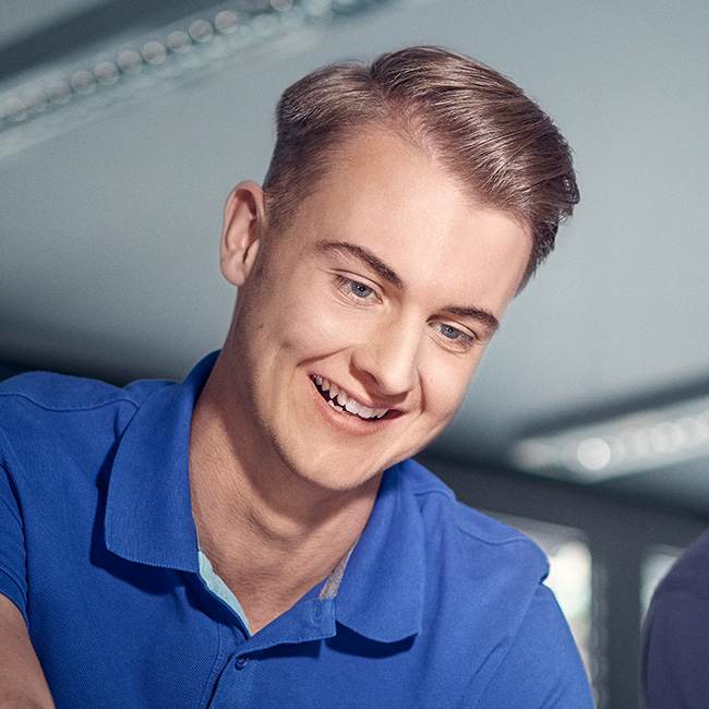IT-Spezialist Marius lächelt, er hat blonde Haare, die zur Seite gegelt sind und blaue Augen.