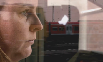 Eine Frau, die durch ein Fenster auf einen roten Zug schaut.
