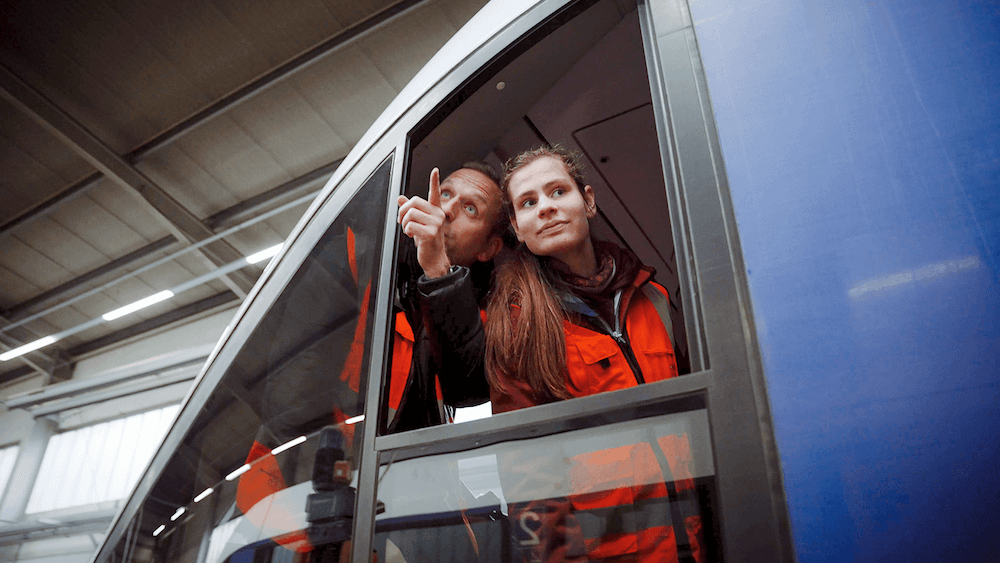 Ein Lokführer und ein Mädchen gucken aus einem Fenster
