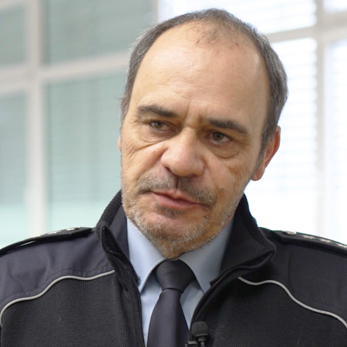 Polizist Jürgen Groten steht vor einer Bildschirm-Präsentation.