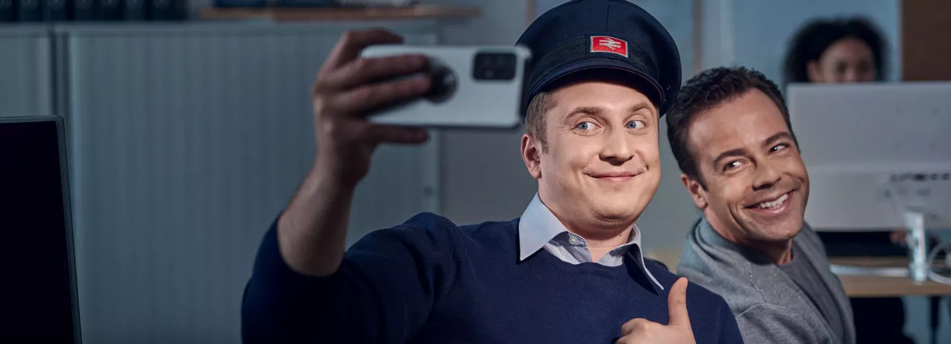 Ein Betriebsplaner zeigt einen Daumen nach oben und macht mit einer weiteren Person ein Selfie.