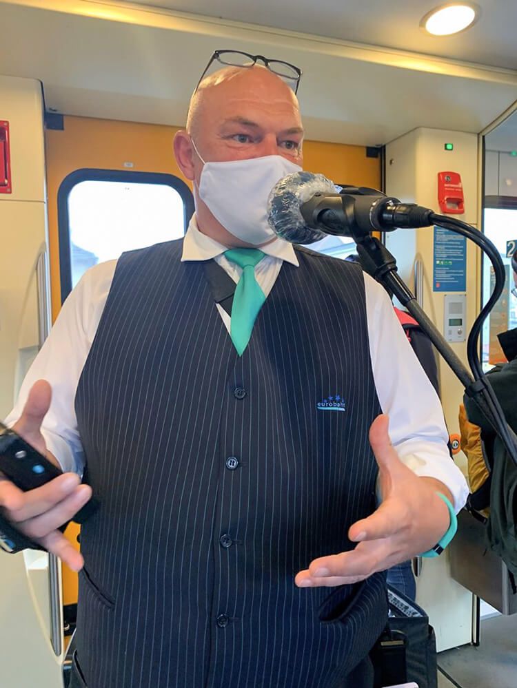Ein Portrait eines Kundenbetreuers mit Atemschutzmaske und Arbeitskleidung.