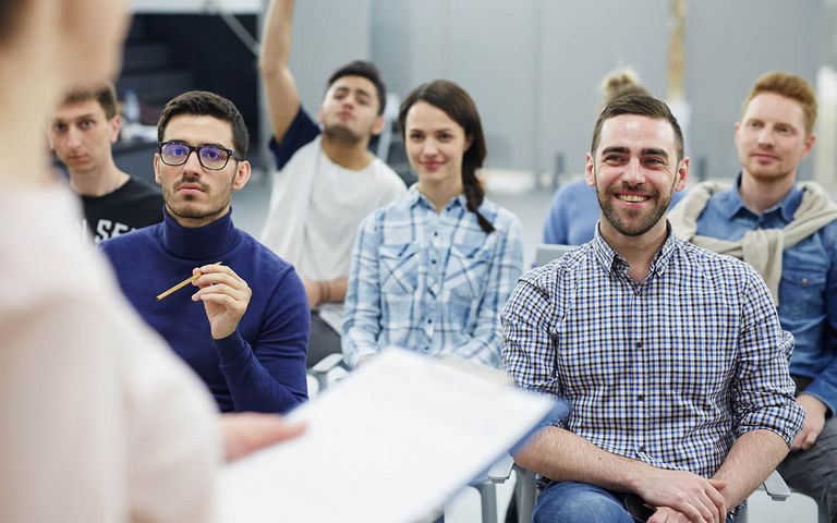 Mehrere Umschüler sitzen in einer Unterrichtseinheit und stellen Fragen zum Unterrichtsstoff.