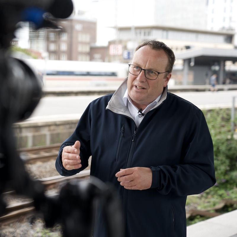 NRW-Verkehrsminister Oliver Krischer vor einer TV-Kamera am Essener Hauptbahnhof.