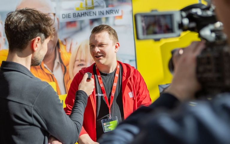 Ein Reporter führt ein Interview mit einem Personaler der DB Regio auf einer Jobmesse