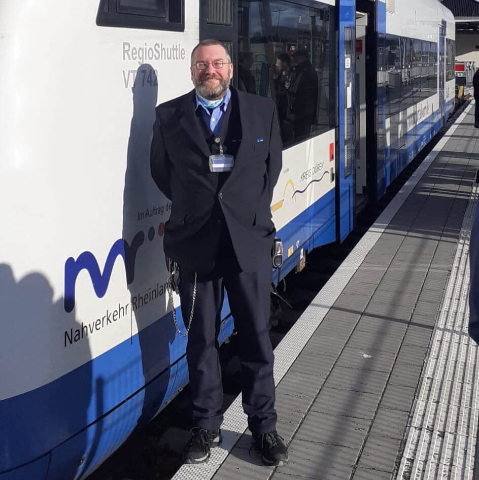 Ein Kundenbetreuer steht neben einer Bahn.