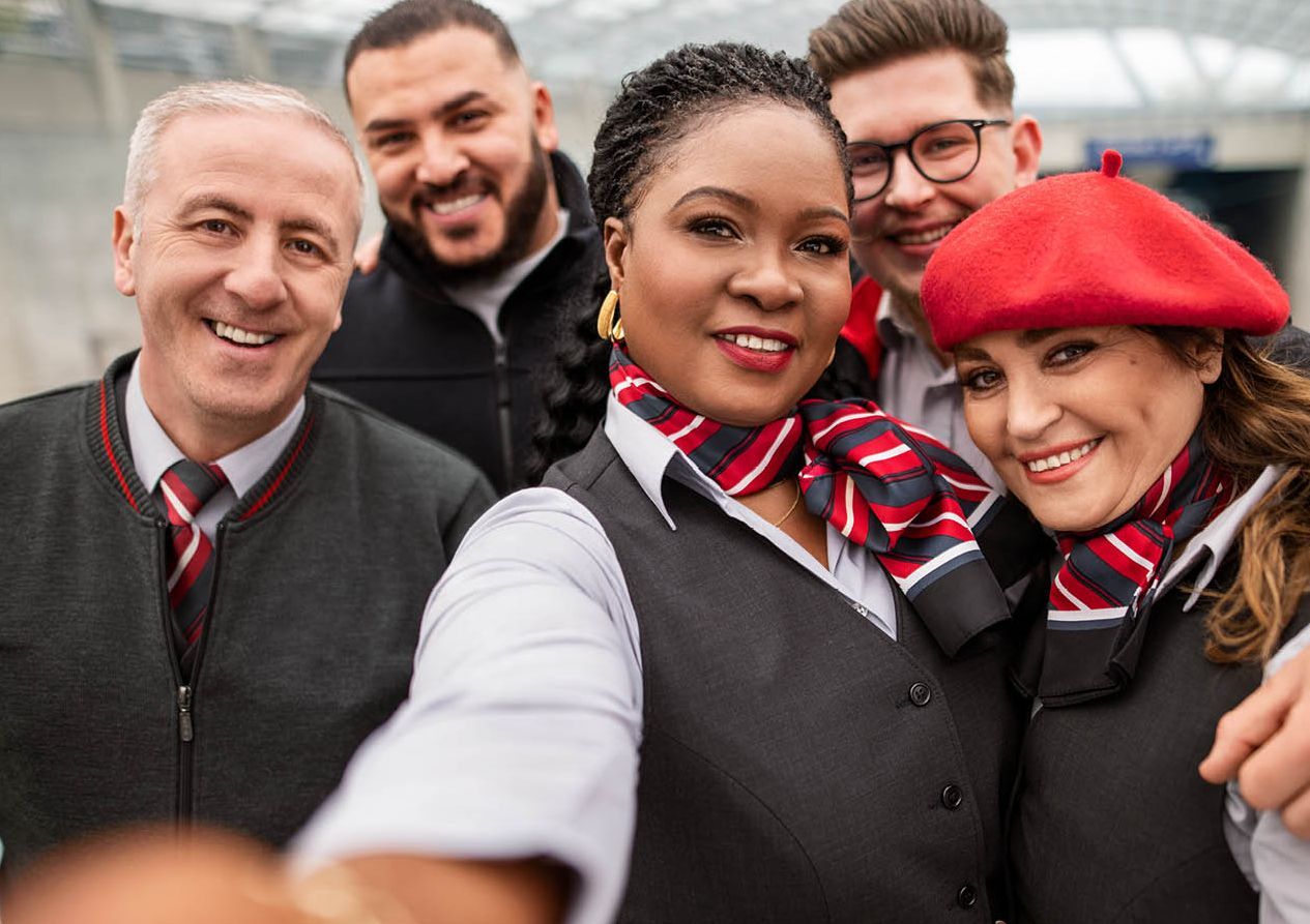 EIne Gruppe Bahner*innen macht ein Selfie am Bahnsteig. Vier Personen lachen in die Kamera.