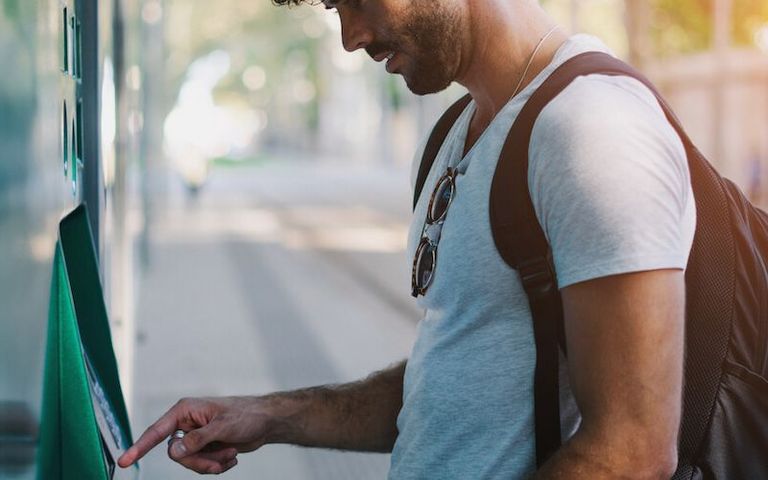 Ein junger Mann steht an einem ÖPNV Ticketautomat und möchte ein Ticket kaufen. 