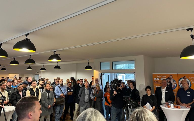 Viele Menschen stehen versammelt und hören einer Rede zu.