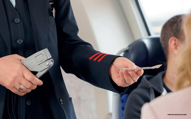 Ein Kontrolleur gibt einem Fahrgast sein Ticket zurück.