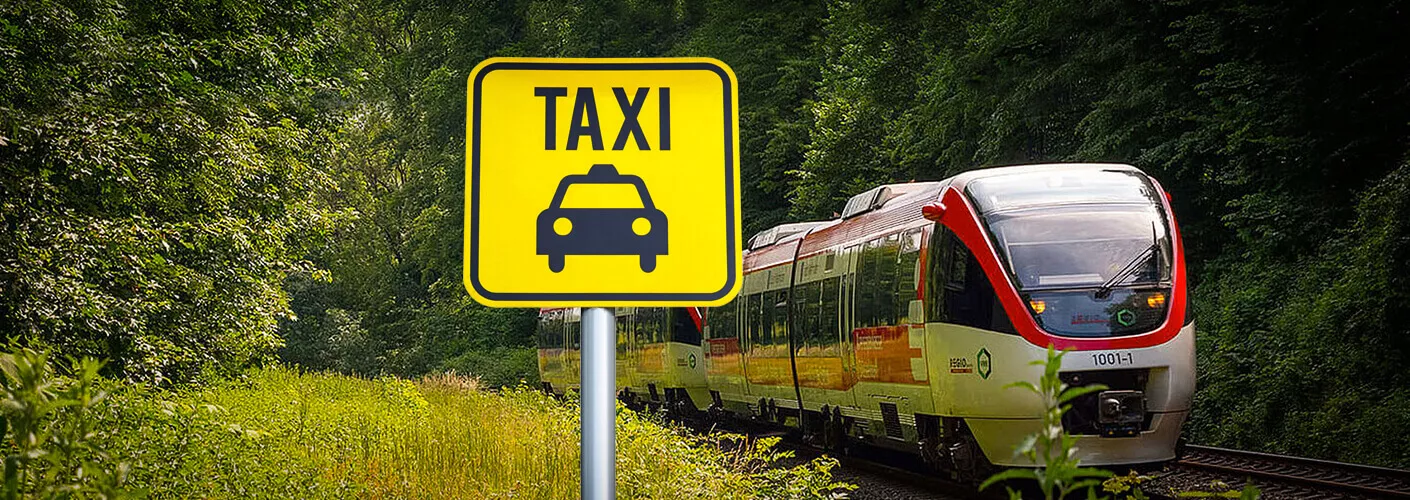 Ein Zug fährt neben einem Taxi-Schild vorbei