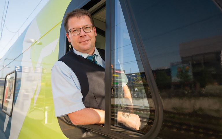 Tim Plogmann schaut aus dem Führerhaus einer Bahn der WestfalenBahn. 