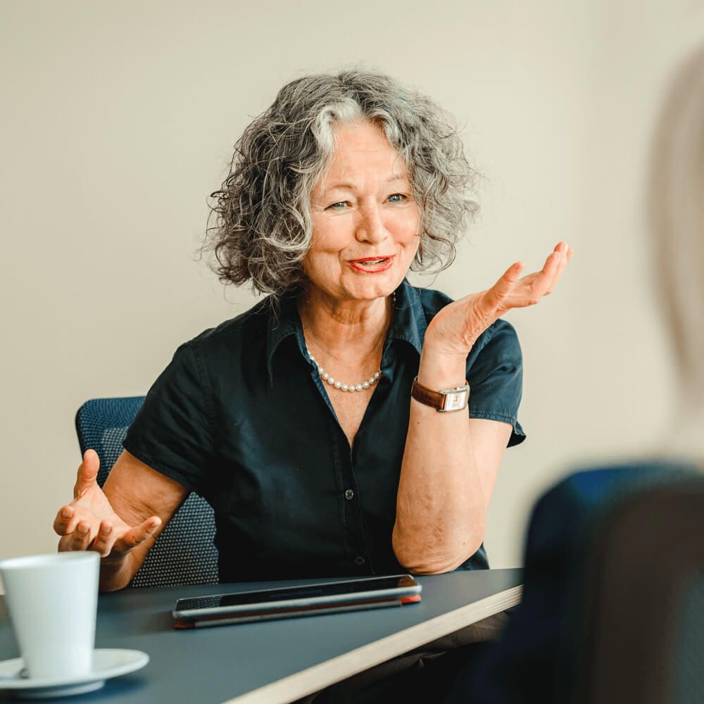 Barbara Tünnemann sitzt redend am Tisch