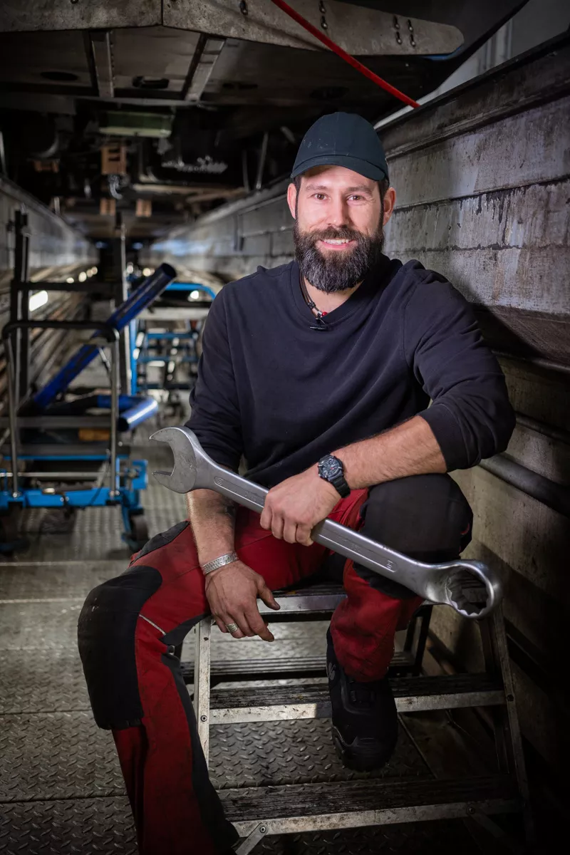 Ein Mechaniker sitzt in einer Werkstatt auf einem Stuhl.