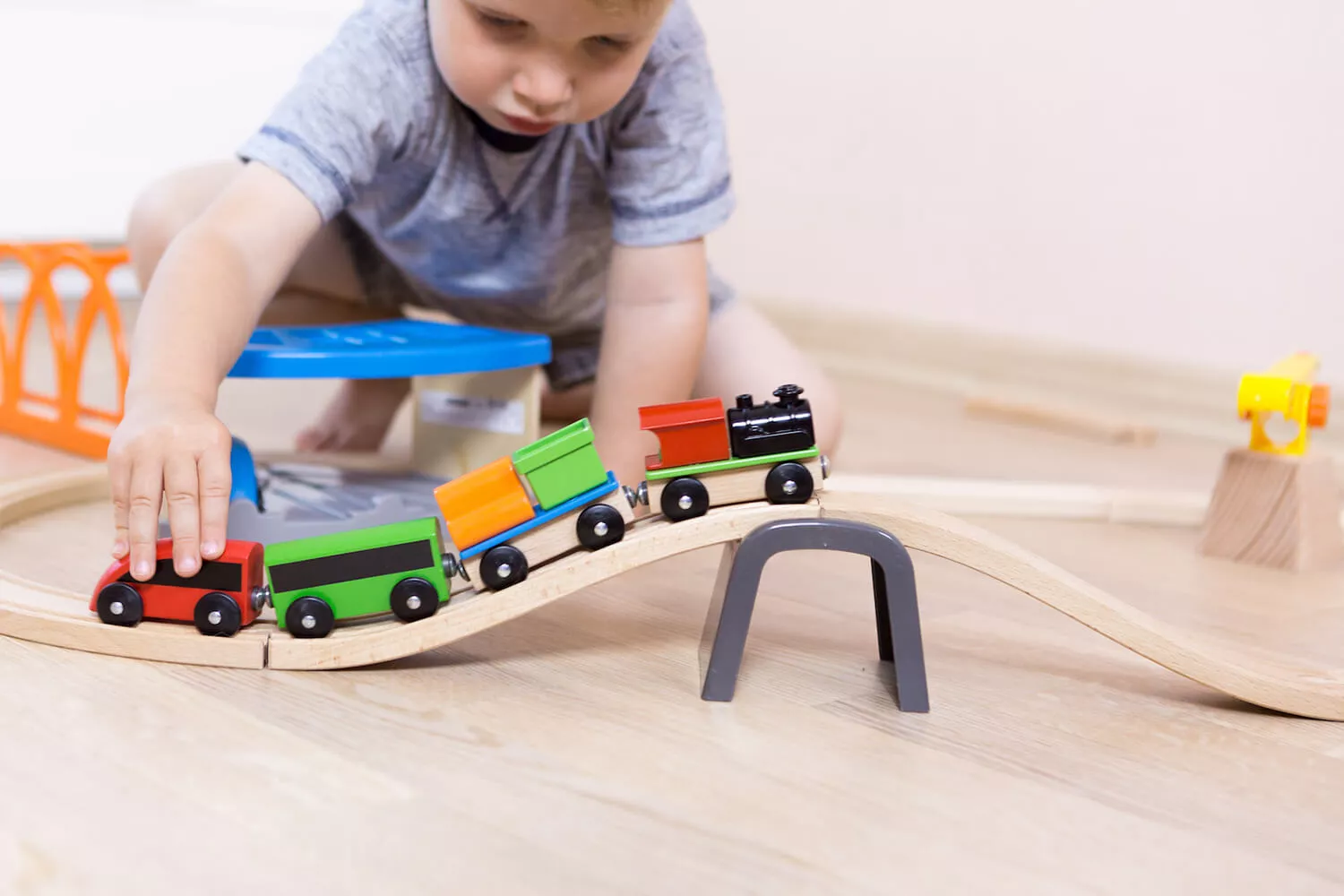 Ein kleines Kind spielt mit einer Holzeisenbahn.
